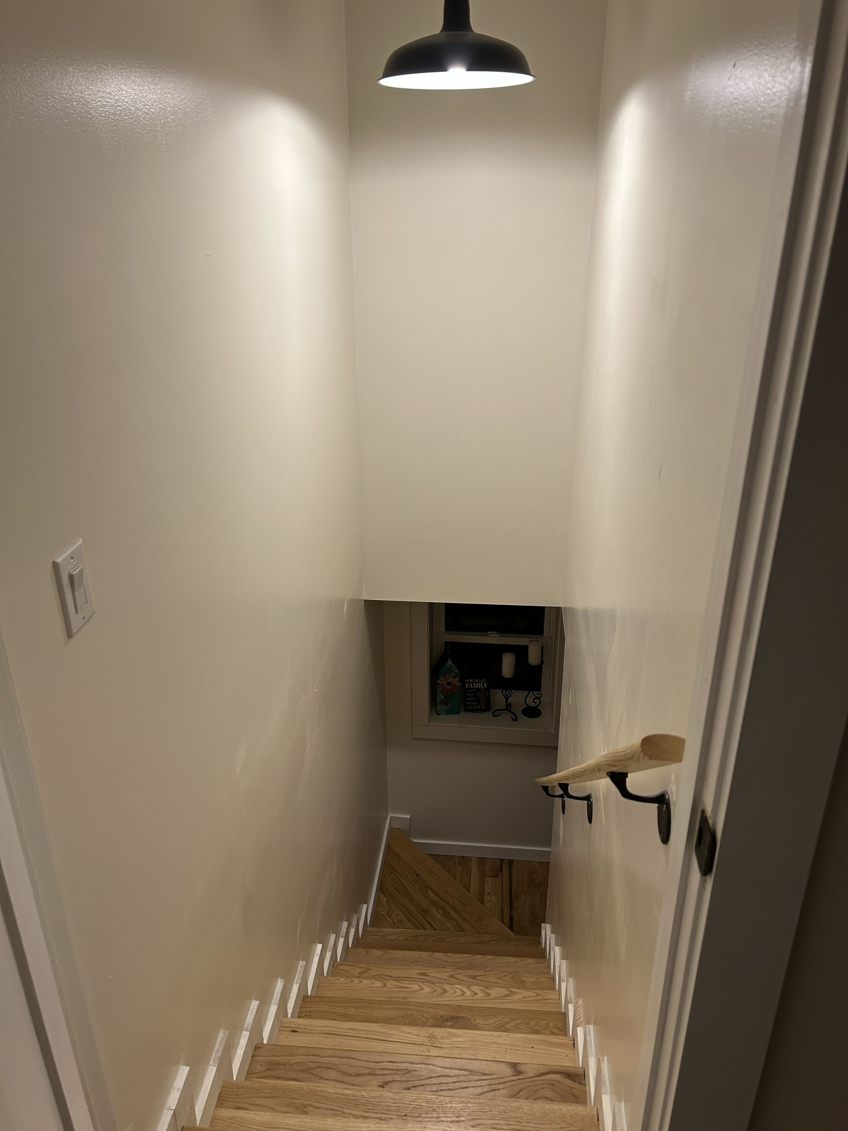 A narrow stairway with wooden steps and a black pendant light.