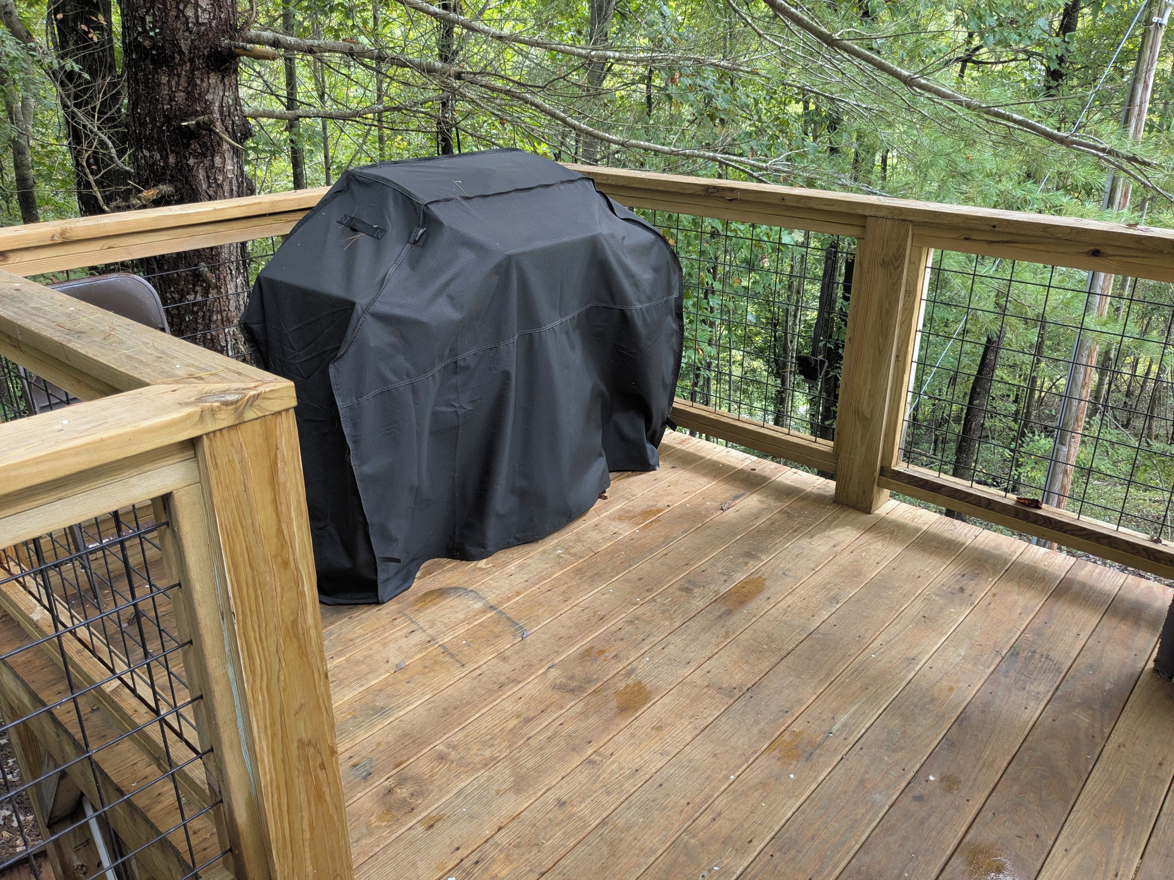 A wooden deck with a grill and a covered seating area.
