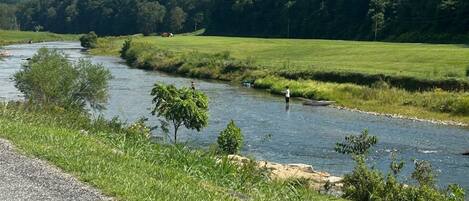 A river flowing through a green landscape with a road on the side.