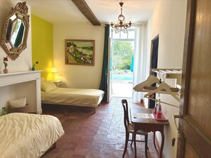 Un dormitorio con una cama, un escritorio con silla, un cuadro en la pared y una ventana con vistas al exterior.