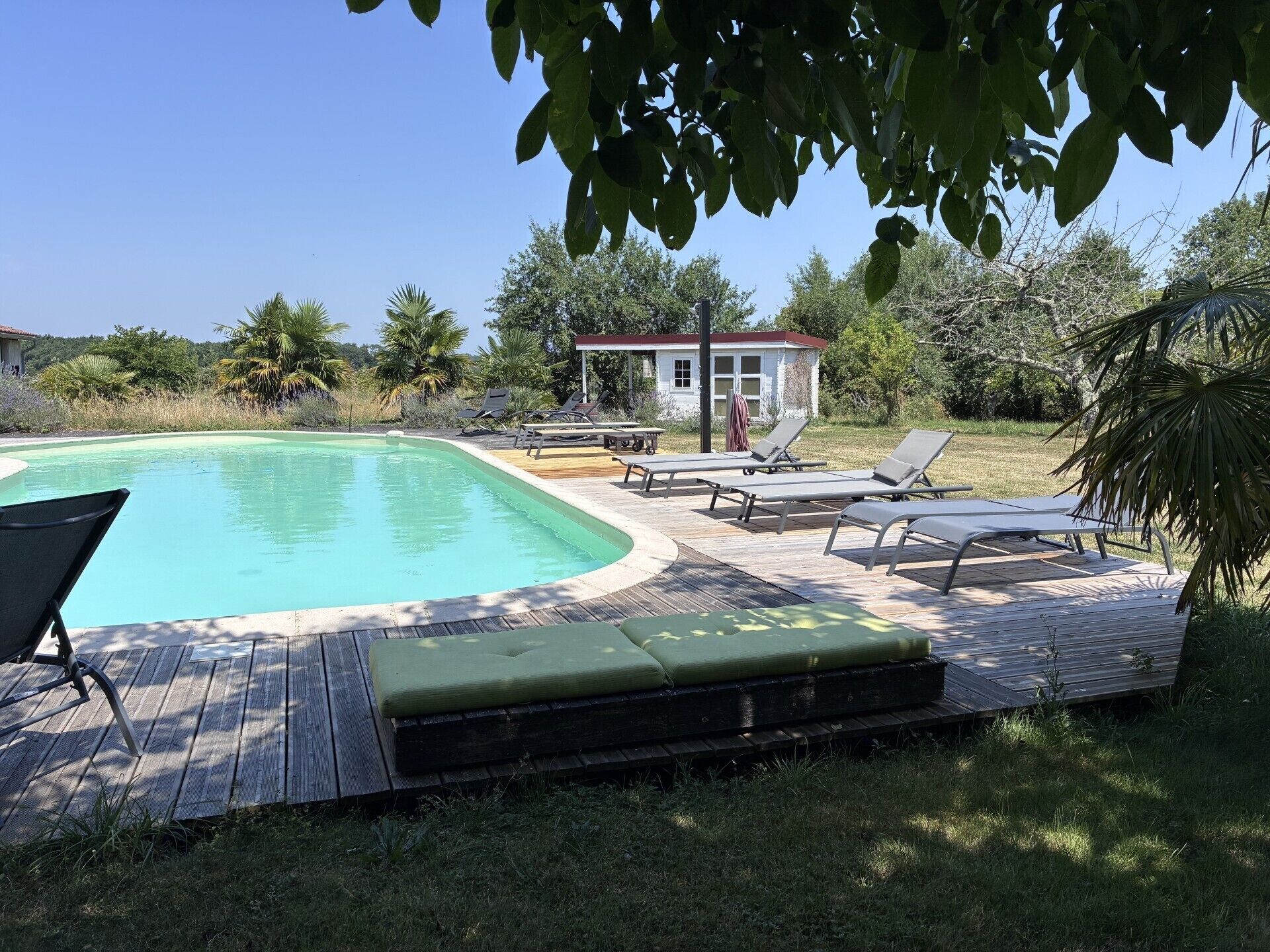 A swimming pool with lounge chairs and a small building in the background.