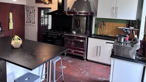A kitchen with a central island, a stove, a range hood, and various kitchen utensils. - Maison Laurent - The Gers, at the end of the road. (Margouët-Meymes)