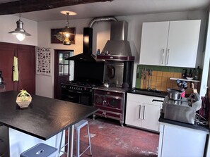 Una cocina con una isla central, estufa, extractor de humos y diversos utensilios de cocina.