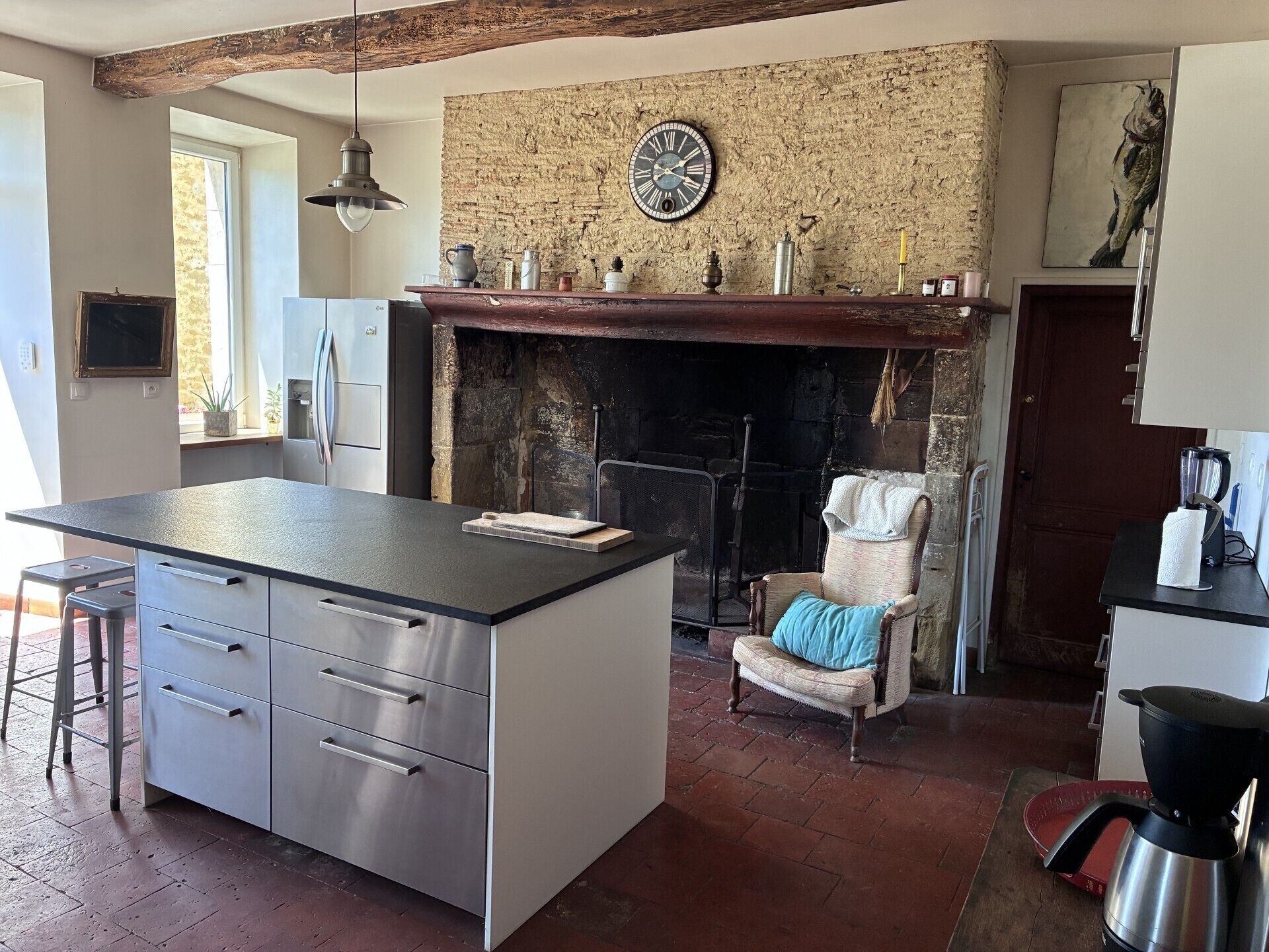 A kitchen with a central island, a fireplace, and a stone wall.