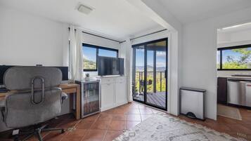 A modern kitchen with a view of the outdoors, a dining area with a table and chairs, and a workspace with a desk and chair.