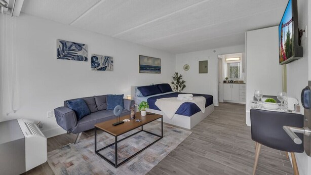 Ett modernt vardagsrum med en soffa, ett soffbord och en säng i en blå och vit färgskala.