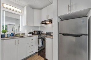 A modern kitchen with stainless steel appliances, white cabinetry, and a built-in microwave. - Comfy Suite 7 Min to Disney World + Parking | Orl (Kissimmee)