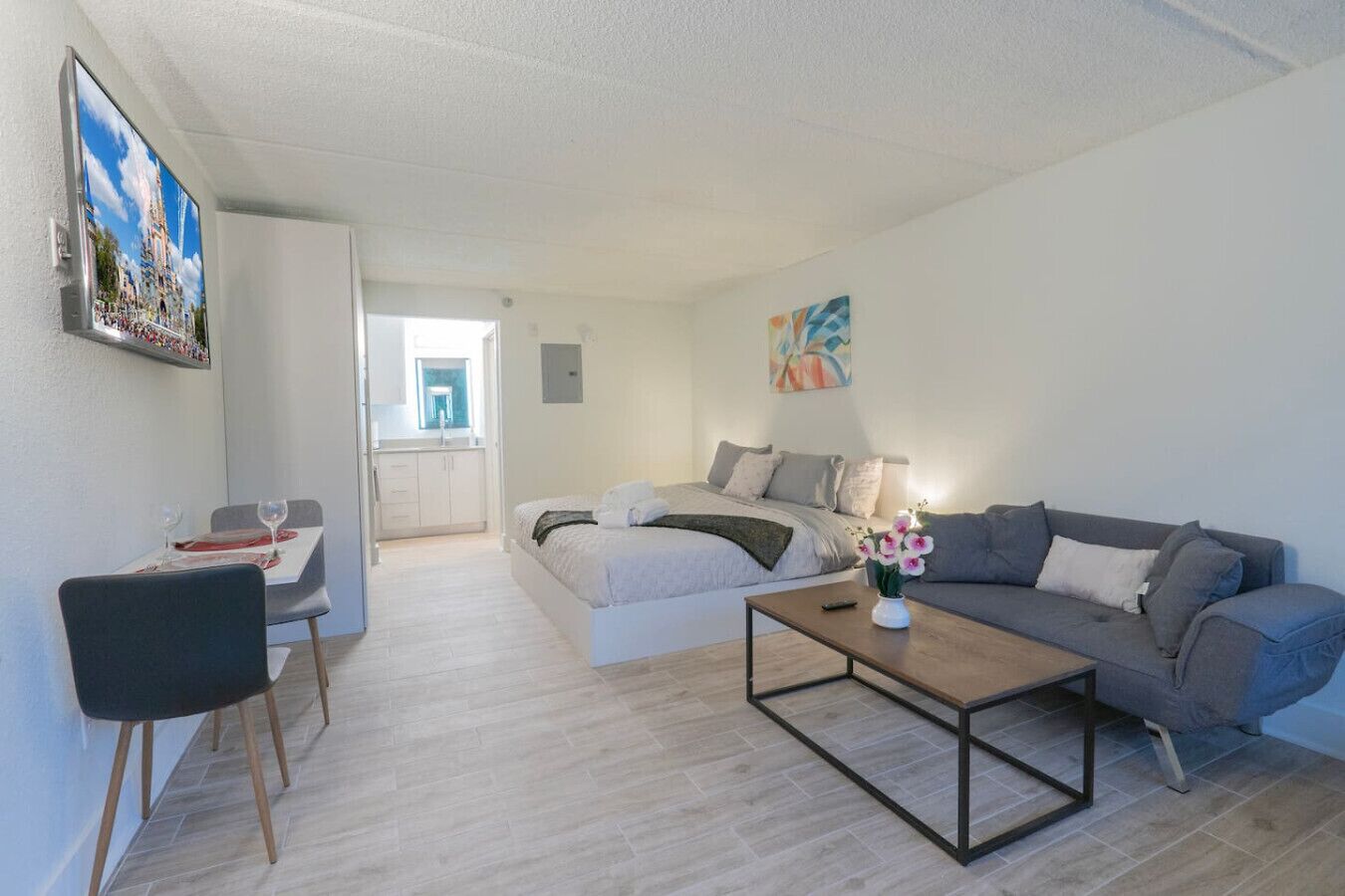 A modern living room with a sofa, a coffee table, and a dining area with chairs and a table set for two.
