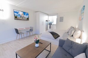 Ett modernt vardagsrum med en soffa, ett soffbord och en matplats med stolar.