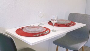 Ruokapöytä, jonka päällä on kaksi punaista aluslautasta, hopeaesineitä ja viinilaseja.