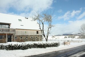 A building with a stone facade, a balcony, and a snow-covered landscape. - La Banne - SAINT SAUVES D'AUVERGNE (SAINT SAUVES D'AUVERGNE)