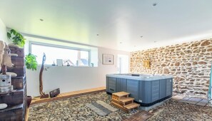 Ein modernes Badezimmer mit Steinwand, Whirlwanne und einer Holzbank.