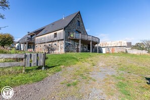 A stone building with a wooden deck and a fenced yard. - La Banne - SAINT SAUVES D'AUVERGNE (SAINT SAUVES D'AUVERGNE)