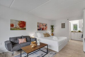 Un saló modern amb un sofà, una taula de centre i un llit. Hi ha quadres a la paret i una planta a un costat.