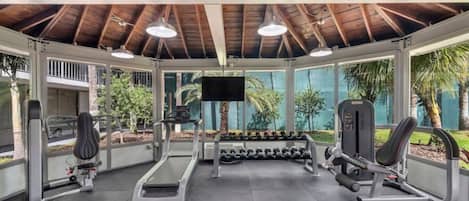 Een overdekte sportschool met loopbanden, gewichten en fitnessapparatuur.