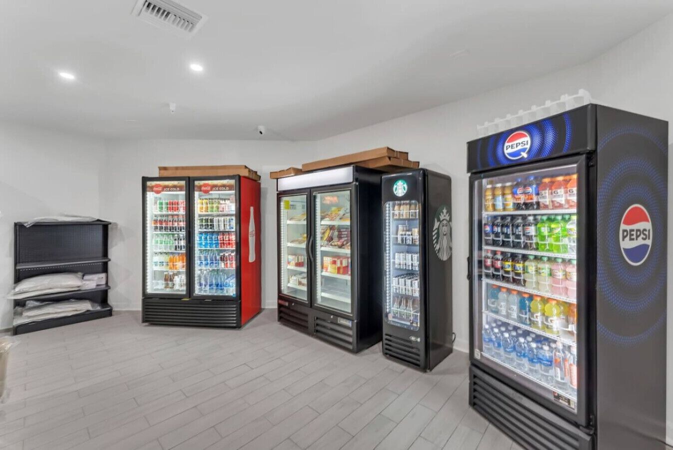 Una fila de máquinas expendedoras de bebidas con logotipos de Pepsi y Coca-Cola, y una máquina de Starbucks.