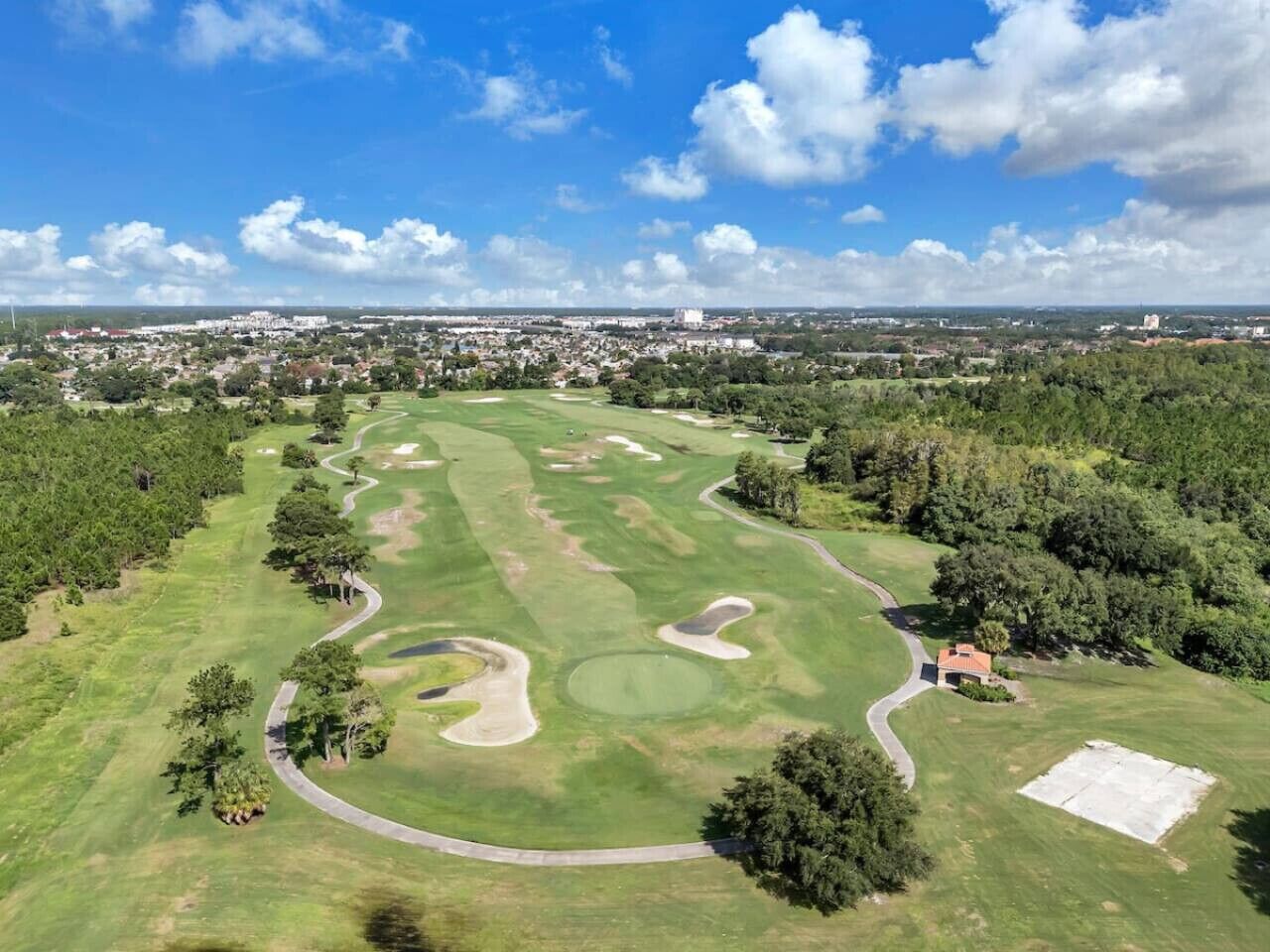 Eine Vogelperspektive eines Golfplatzes mit mehreren Grüns, Sandbunkern und einem Clubhaus.