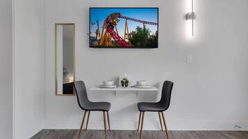 Un coin repas moderne avec une table blanche, deux chaises, un tableau encadré au mur et un miroir.