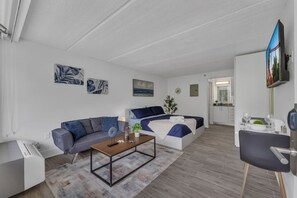 A modern living room with a sofa, a coffee table, and a bed with a blue and white color scheme. - Magic Stay Near Disney Parks | Orl (Kissimmee)