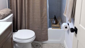 A bathroom with a toilet, shower curtain, and towel rack. - Modern 3BD Central Phoenix Home (Phoenix)