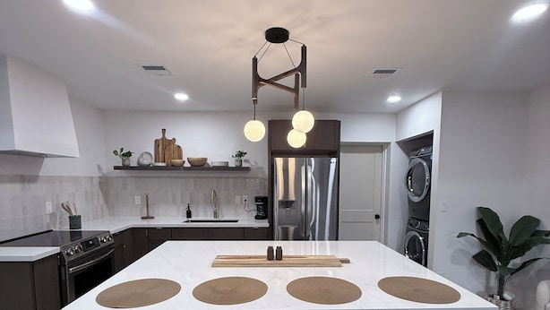 A modern kitchen with a central island, bar stools, a built-in oven, and a stainless steel refrigerator. - Modern 3BD Central Phoenix Home (Phoenix)