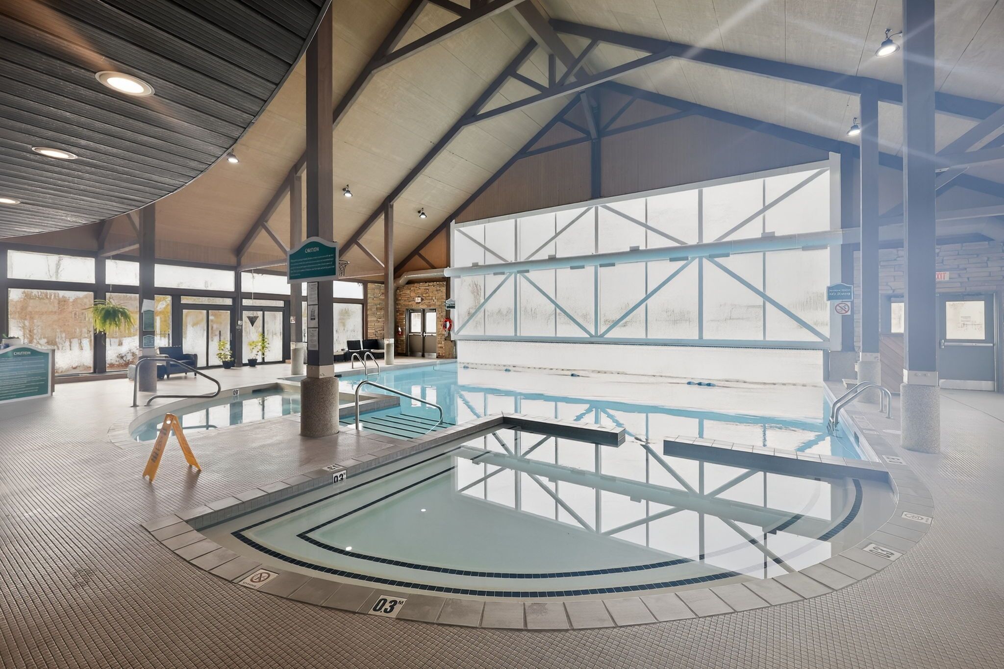 Une piscine intérieure dotée d’un plafond haut et de grandes fenêtres.