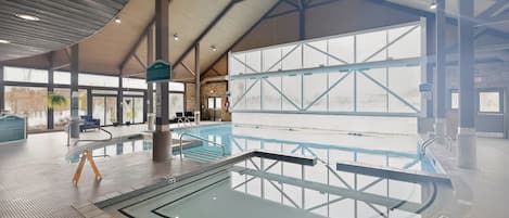 En indendørs swimmingpool med højt til loftet og store vinduer.
