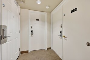 A hallway with three white doors, each with a lock and a keyhole. The doors have labels indicating the year 2014 and 2015. The floor is tiled, and the walls are plain. - Cozy Spacious Resort Suite With Kitchen and Living Room (Oro-Medonte)
