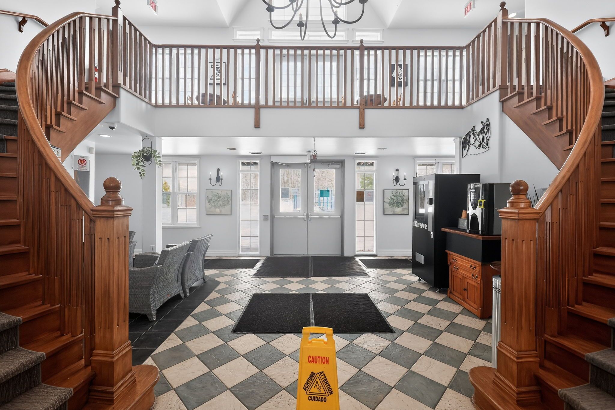 A hotel lobby with a check-in desk, a staircase, and a reception area.