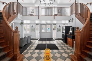 A hotel lobby with a check-in desk, a staircase, and a reception area. - Cozy Spacious Resort Suite With Kitchen and Living Room (Oro-Medonte)