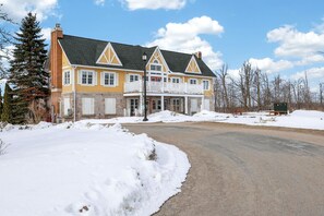A two-story house with a snow-covered driveway and a clear sky. - Cozy Spacious Resort Suite With Kitchen and Living Room (Oro-Medonte)