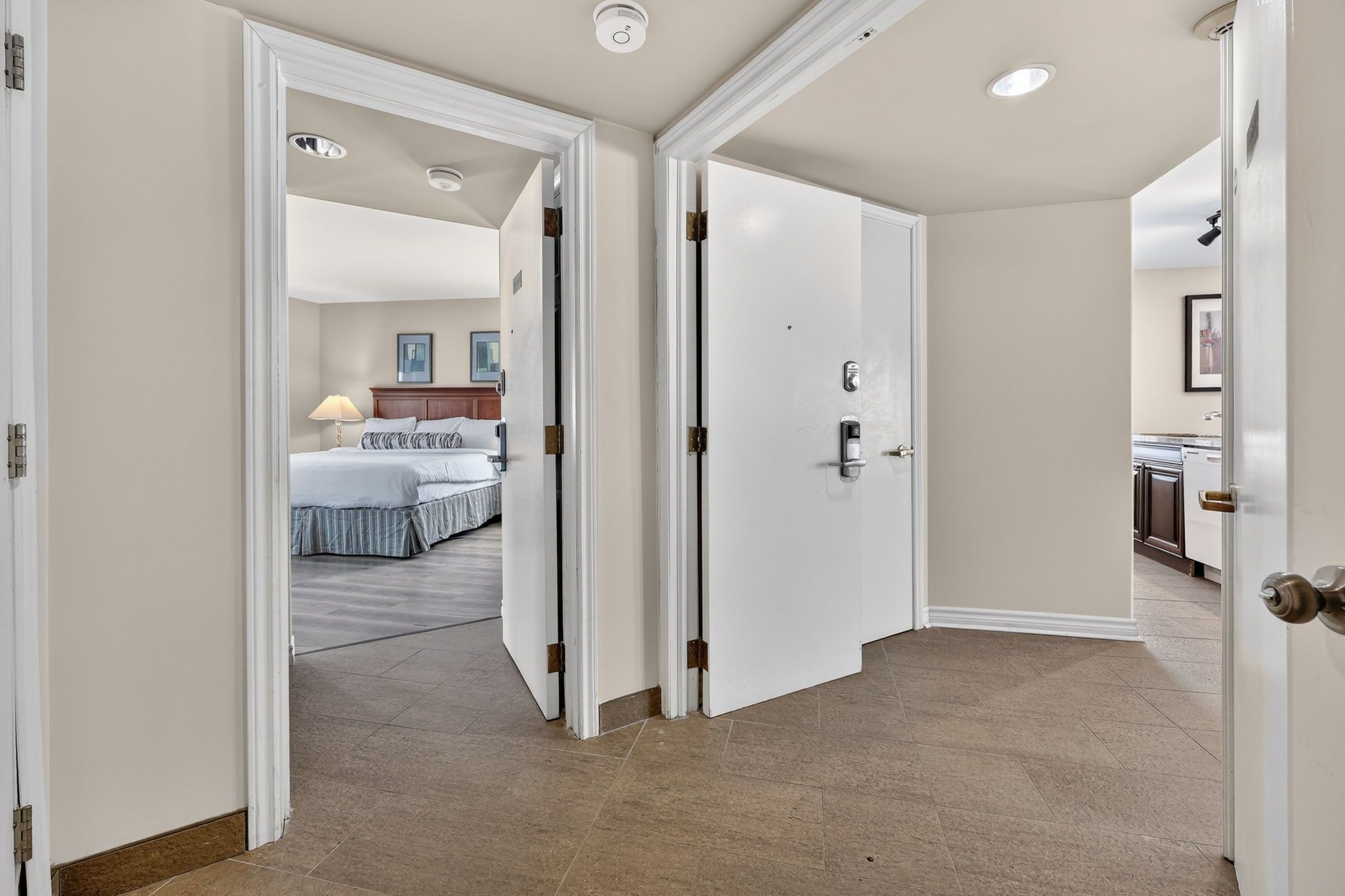 A hotel hallway with a bed, a bathroom, and a kitchen area.