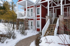 A two-story house with a red exterior, white trim, and a covered porch. - Cozy Spacious Resort Suite With Kitchen and Living Room (Oro-Medonte)