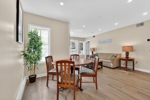 A dining area with wooden chairs and a table, a sofa, a lamp, and a 'WELCOME' sign on the wall. - Cozy Spacious Resort Suite With Kitchen and Living Room (Oro-Medonte)