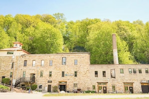 A historic stone building with multiple doors, a staircase, and a chimney.