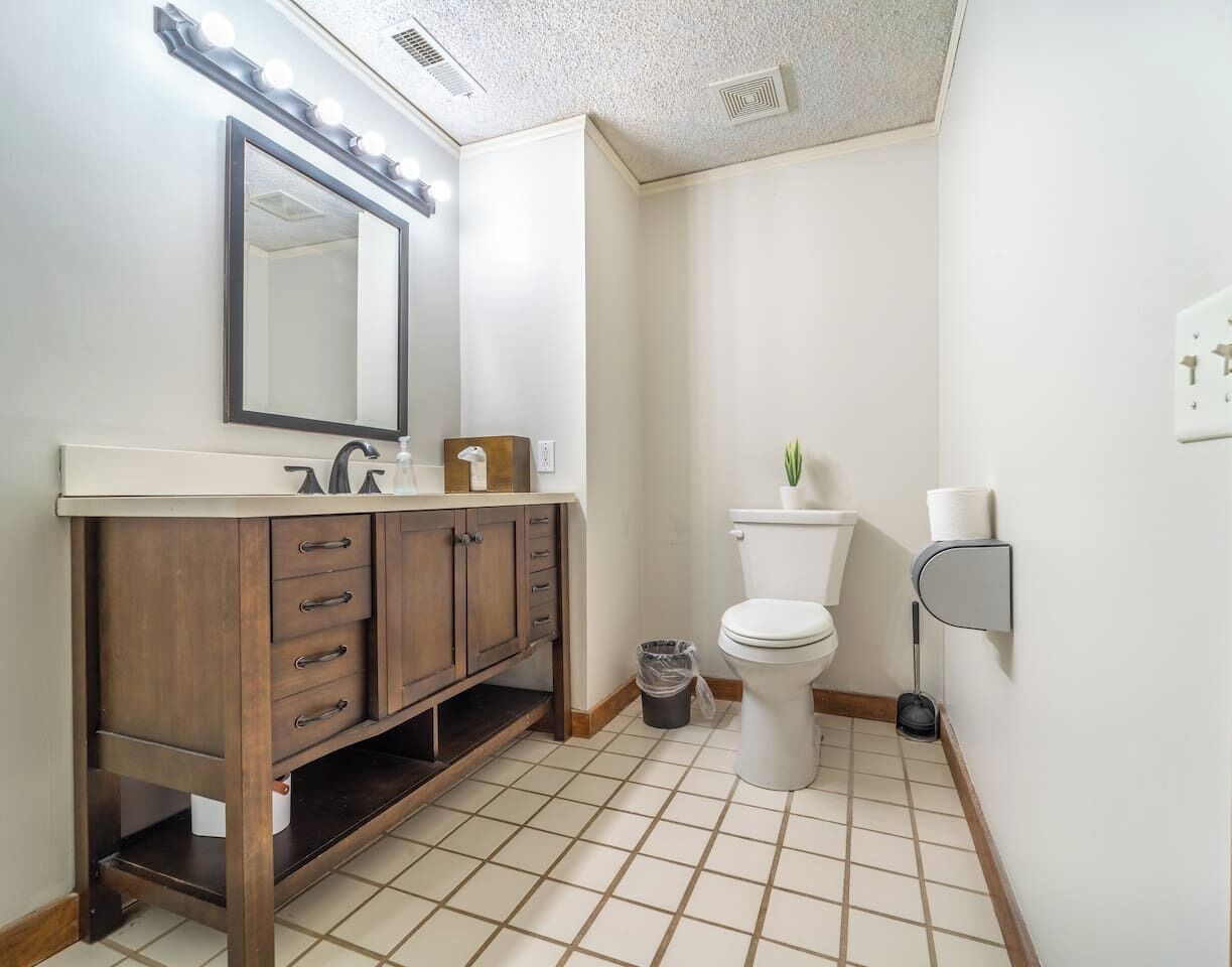 Een badkamer met een wastafel, spiegel, toilet en een prullenbak.