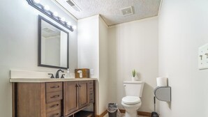 Un bagno con lavabo, specchio, WC e cestino.