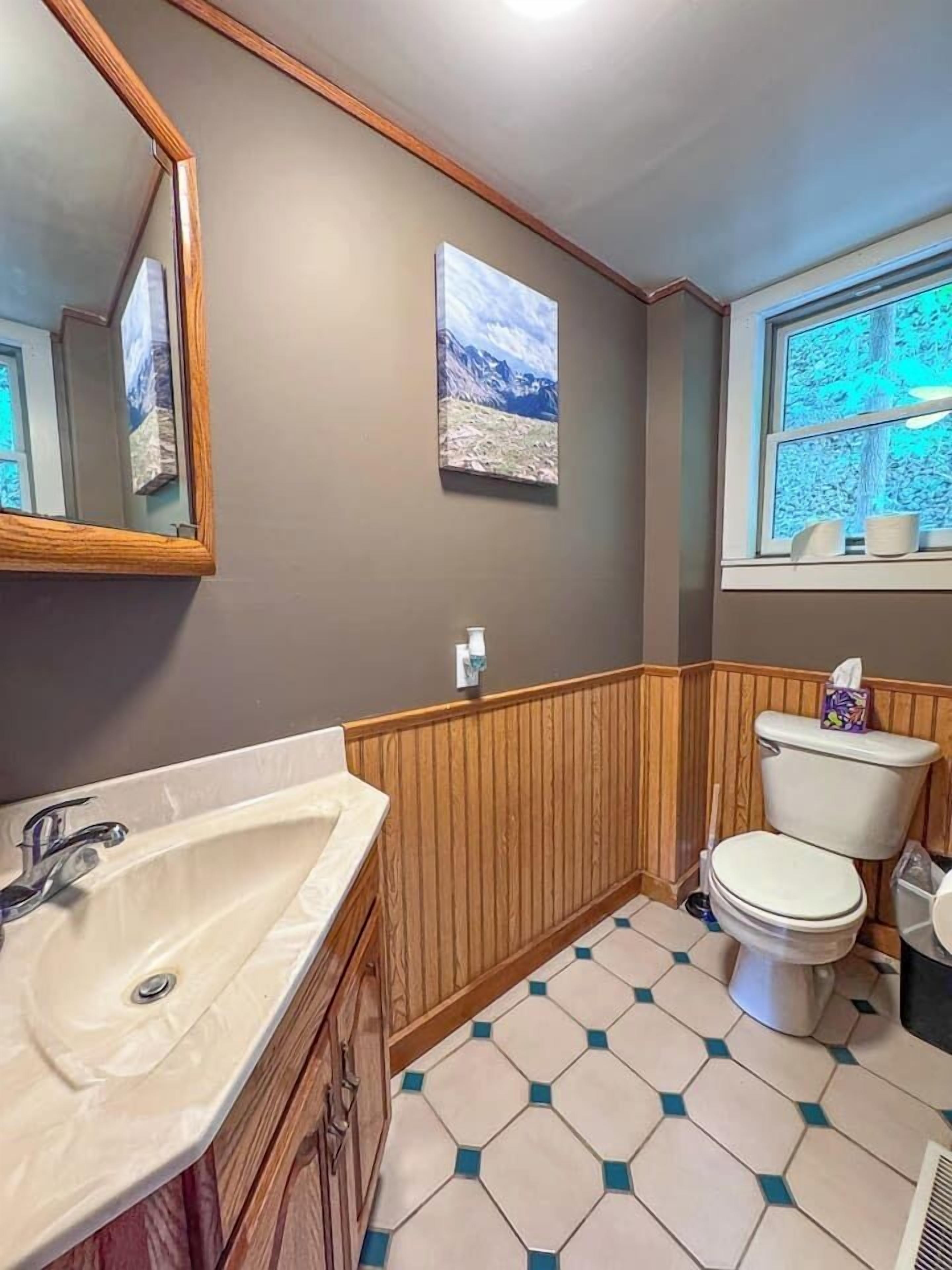 A bathroom with a sink, toilet, and window.