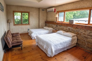 Una habitación con dos camas, un sofá y una pared de piedra.