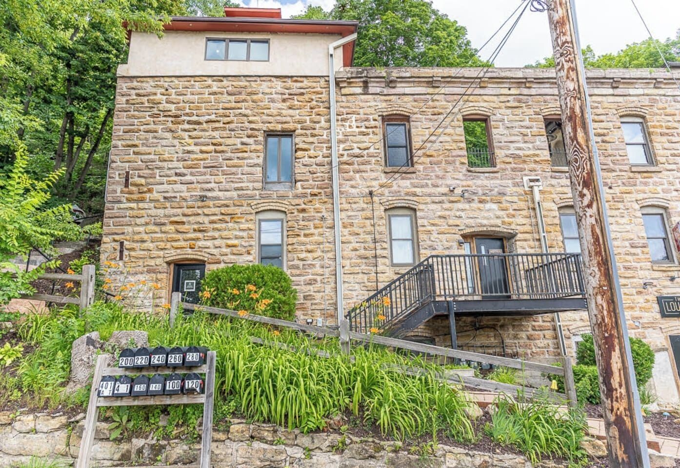 A stone building with a balcony, a mailbox, and a sign with house numbers.