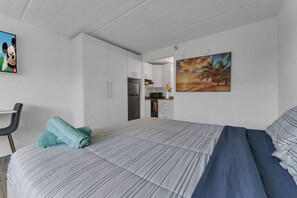 Ein modernes Hotelzimmer mit einem großen Bett, einem Schreibtisch und einer Küchenzeile.