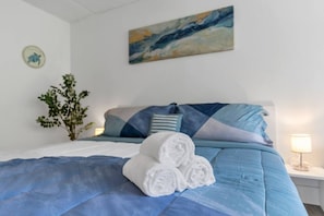 A neatly made bed with blue bedding, a pillow, and rolled towels on the bed. - Disney Area Condo w/ Pool + Free Parking | Orl (Kissimmee)