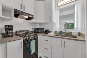 Eine moderne Küche mit Herd, Mikrowelle, Kaffeemaschine und einem Fenster mit Blick.