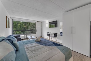 A modern bedroom with a large bed, a desk, and a TV. - Disney Area Condo w/ Pool + Free Parking | Orl (Kissimmee)