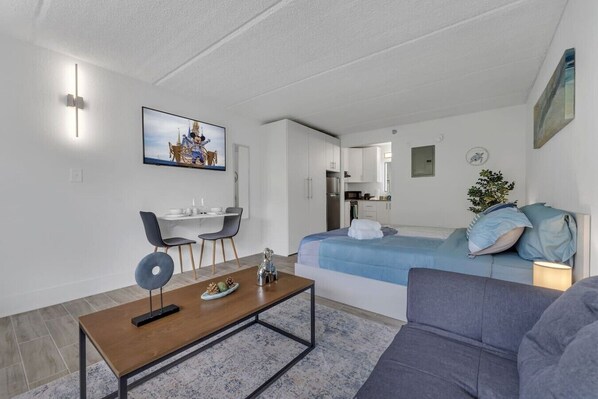 Una sala moderna con comedor, kitchenette y un dormitorio con cama y mesita de noche.