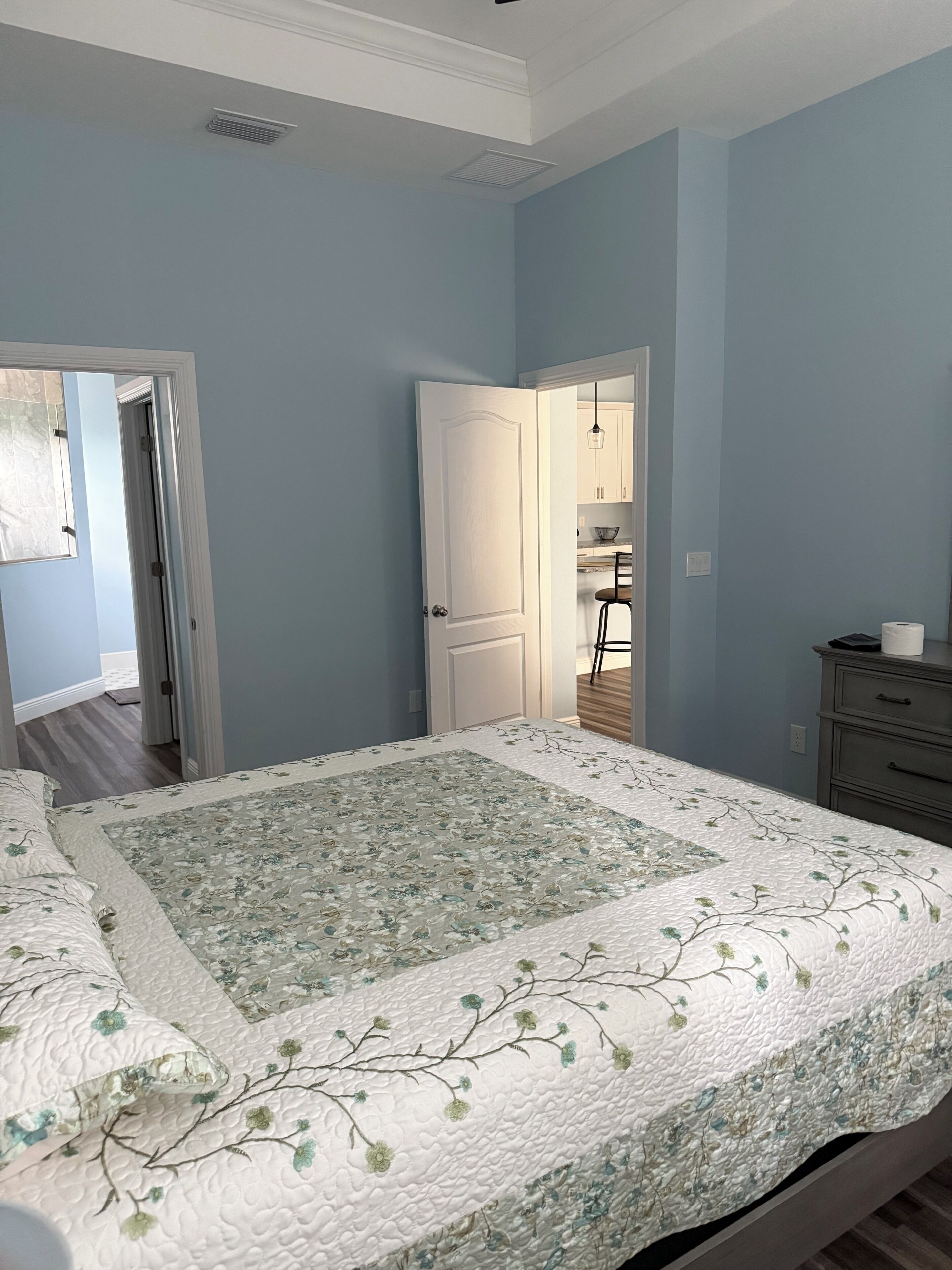 Ein Schlafzimmer mit einem Bett, einer Kommode und einer Tür zu einem Badezimmer.