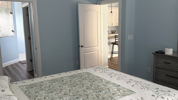 A bedroom with a bed, a dresser, and a door leading to a bathroom.