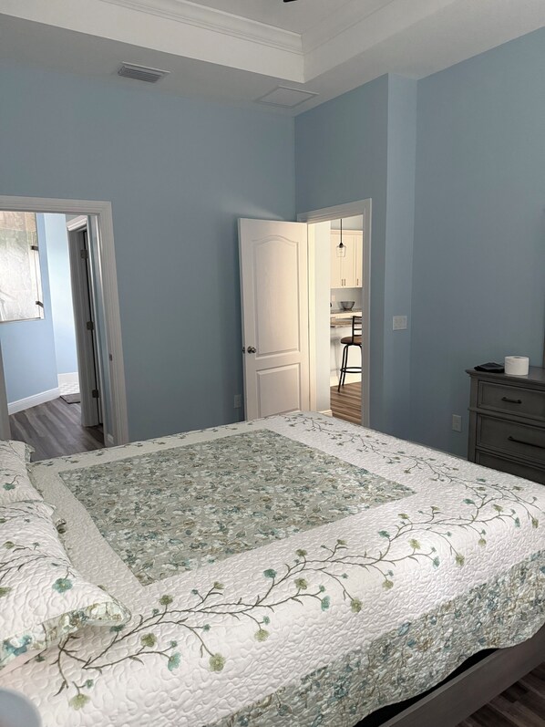 A bedroom with a bed, a dresser, and a door leading to a bathroom.