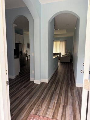 An interior with a kitchen, living area, and a hallway with wooden flooring.