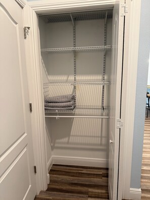 A closet with open doors, wooden flooring, and metal shelving. - Furnished 3 bedroom, easy I-4 Access (Plant City)